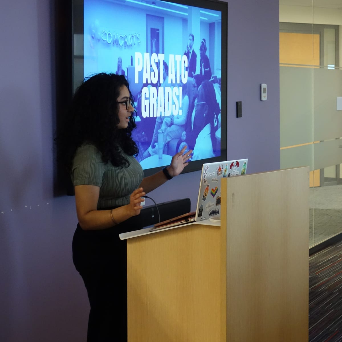 Sneha presenting to a room in front of a large screen